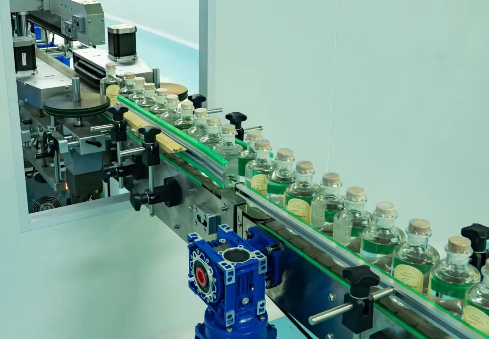 Reed diffuser bottles moving through a production labeling line
